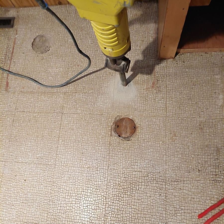Breaking through a basement floor to reach the main sewer during a backwater valve install